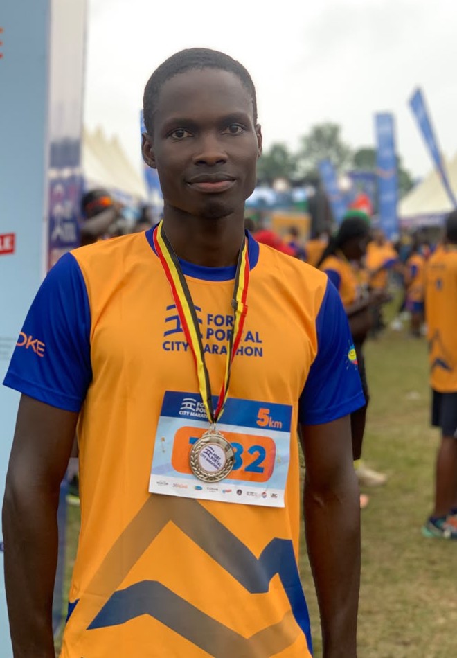 Joseph Ssemuli at the Fort Portal City Marathon finish area, wearing a finisher's medal